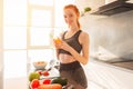 Athletic young red haired woman in the kitchen with a glass of fruit centrifuged juice