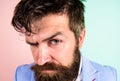 Keep hair tidy and care about hairstyle. Man bearded hipster on strict face pink blue background. Barber tips grooming