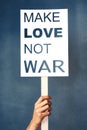 Keep hate out of society. Studio shot of an woman holding a sign that says make love not war against a blue background. Royalty Free Stock Photo