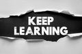 KEEP LEARNING inspiring phrase visible behind torn paper, concept for education, personal growth, or continuous improvement Royalty Free Stock Photo