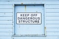 Keep off dangerous structure sign on duck egg coloured wooden wall Royalty Free Stock Photo