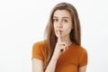 Keep our little secret. Feminine tender caucasian woman with fair hair, saying shh while showing shush gesture with Royalty Free Stock Photo