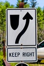 A keep right information sign with trees in the background