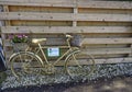 A Keep Scotland beautiful Bike with Flower display stands propped up against a wooden Fence.