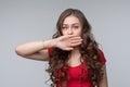 Young woman covering mouth with hand, looking serious, promises to keep secret. Silence and secret concept Royalty Free Stock Photo