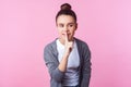 Keep in secret! Portrait of playful positive brunette teen girl showing hush silence gesture, isolated on pink background