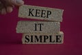 Keep it simple symbol. Concept word Keep it simple on beautiful brick blocks. Businessman hand. Beautiful red background. Business
