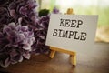 Keep simple text on paper card with wooden easel on wooden table background, inspiration motivation concept