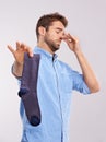 Keep this sock away from me. Studio shot of a handsome young man holding an unpleasant smelling sock against a gray