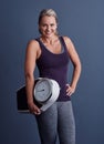 Keep track of your weight. Studio portrait of an attractive mature woman holding a weightscale against a blue background Royalty Free Stock Photo