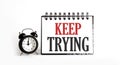 Keep Trying. notepad writing on the white background with alarm clock Royalty Free Stock Photo