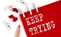 KEEP TRYING text on red paper with office tools on white background Royalty Free Stock Photo