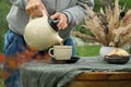 Keep warm, fall tea party. Autumn mood. Female hands pouring tea in mug, drinking tea outdoors. Royalty Free Stock Photo