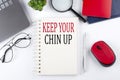 KEEP YOUR CHIN UP text on a notepad with laptop on the white background Royalty Free Stock Photo
