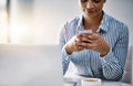 Keep your contacts close at hand. a young businesswoman using a cellphone in an office.