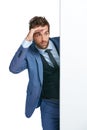 Keep your eyes peeled for business competitors. Studio shot of a handsome businessman peering around a wall against a