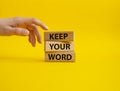 Keep your word symbol. Wooden blocks with words Keep your word. Beautiful yellow background. Businessman hand. Business and Keep