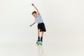 Keeping balance. Playful, active kid, boy riding on skateboard over grey studio background. Concept of game, childhood Royalty Free Stock Photo