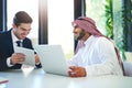 Keeping business collaborative and productive. a young muslim businessman using a laptop and digital tablet with his