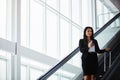 Keeping business moving. a businesswoman traveling down an escalator in an airport.