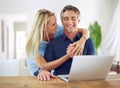 Keeping connected. a happy mature couple using a laptop at home.