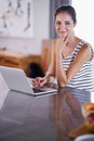 Keeping connected at home. an attractive young woman using her laptop in the kitchen.