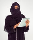 Keeping connected to her world. Studio shot of a woman in a burqa using a digital tablet.