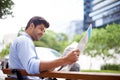 Keeping an eye on investments. A handsome young businessman reading a newspaper while sitting on a bench in the city. Royalty Free Stock Photo