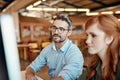 Keeping their office culture a collaborative one. a young businesswoman and mature businessman using a computer together Royalty Free Stock Photo