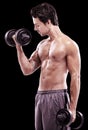 Keeping well-toned. Side view of a bare-chested young man lifting dumbbells isolated on black. Royalty Free Stock Photo