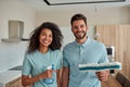 Keeping your home super clean. Happy male and female professional cleaners in uniform holding cleaning supplies, looking