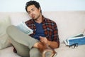 He keeps current on all happenings. A gorgeous young man sitting on a sofa and reading a newspaper with legs crossed.