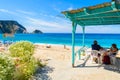 Unidentified couple of tourists sit in traditional greek tavern on Petani beach, Kefalonia island, Greece