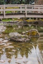 Mossy rocks and koi pond with arched bridge in Japanese Garden