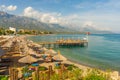 KEMER, TURKEY: Paradise scenery on the pier, umbrellas and sun loungers on the beach and mountains on a sunny day. Royalty Free Stock Photo