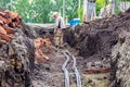 construction engineer or foreman in a white hard hat controls an electric power cable laid in a trench