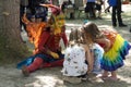 Beautiful girl dressed as fairy at a Renaissance Faire interacting with children in colorful dresses