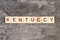 Kentucky word written on wood block, on gray concrete background. Top view.