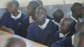 KENYA, KISUMU - MAY 23, 2017: Group of african children sitting in classroom and looking at camera. Little boy clap