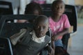 KENYA, KISUMU - MAY 23, 2017: Portrait of happy african boy sitting inside with group of children and dancing, smiling.