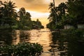 Kerala backwaters scenery at sunset with water canal and houseboat, with warm light and palm trees Royalty Free Stock Photo