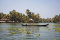 An Indian male fisherman on a traditional wooden boat sails through a channel overgrown with algae Royalty Free Stock Photo