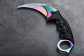 Kerambit dagger with a rainbow-colored blade on a dark textured background. Royalty Free Stock Photo