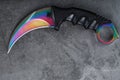 Kerambit dagger with a rainbow-colored blade on a dark textured background. Royalty Free Stock Photo