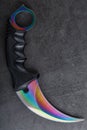 Kerambit dagger with a rainbow-colored blade on a dark textured background. Royalty Free Stock Photo