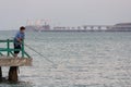 Kerch, Crimea - August 01, 2018: Woman fisherman on the pier against of the Crimean bridge