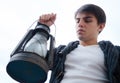 Kerosene lamp. a young man with in his hand against the sky Royalty Free Stock Photo