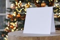 Standing empty square greeting card mock up in front of a christmas tree