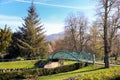 Keswick, Cumbria, UK - April 6th 2019: Distinctive green steel bridge over the River Greta in Fitz Park, on a beautiful sunny day