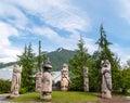 Circle of six American Indian totem poles against mountain background